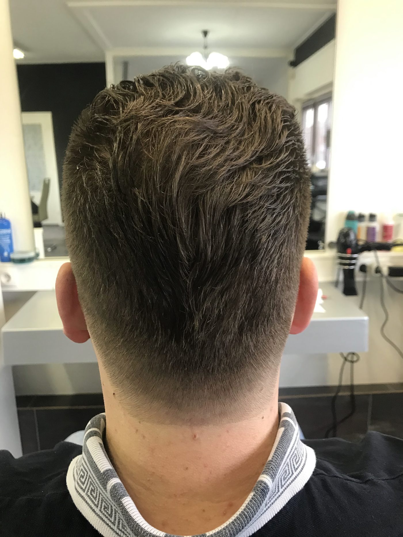 Achterkant van een knipbeurt met een fade en een getextureerde bovenkant, in de zaak